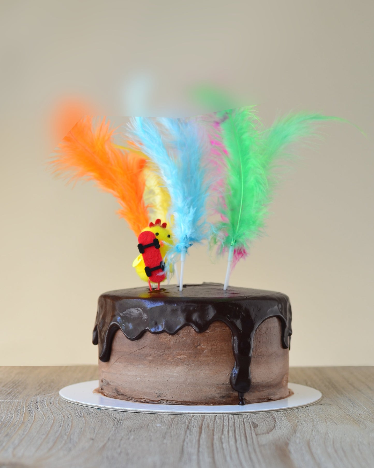 Pastel de chocolate sin frutos secos decorado con plumas y un pollito de pascuas.