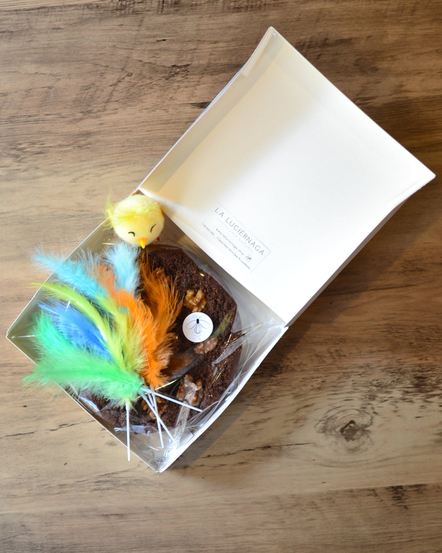 Caja con mona de pascua sin gluten en el interior con pollito y plumas