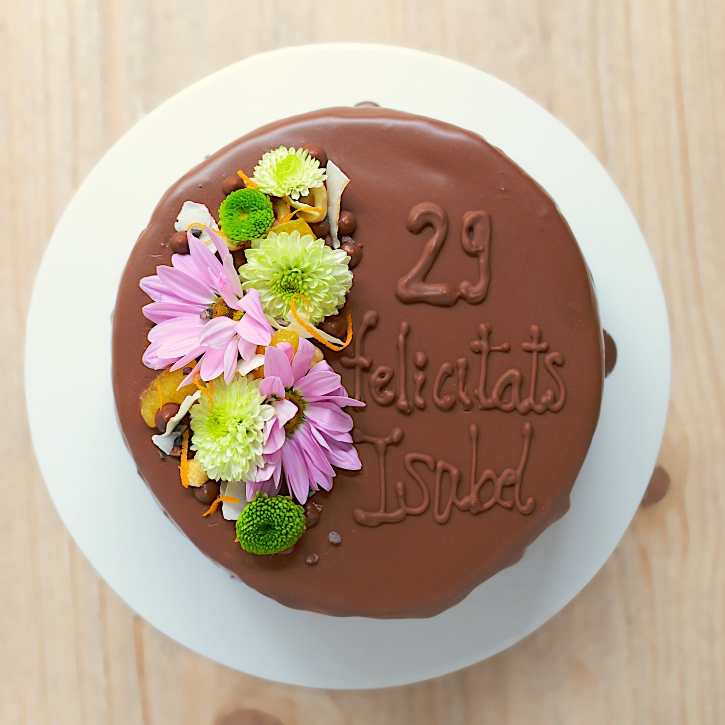 Pastel de chocolate decorado con flores y escrito en chocolate vegano, sin lactosa y sin gluten